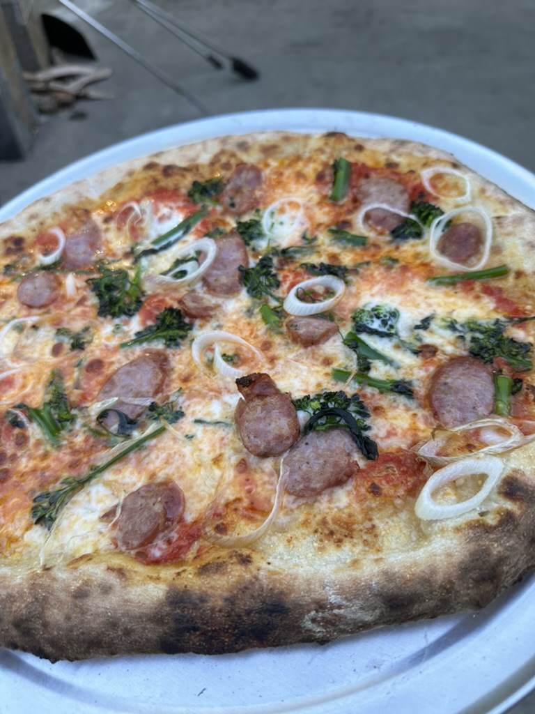 Sausage, broccoli raab, and scallion pizza on a white plate