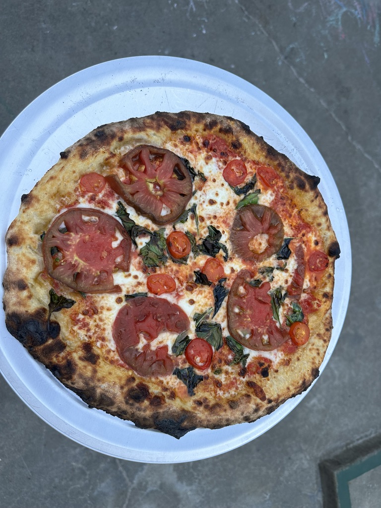 Tomato and fresh basil pizza on a white paper plate