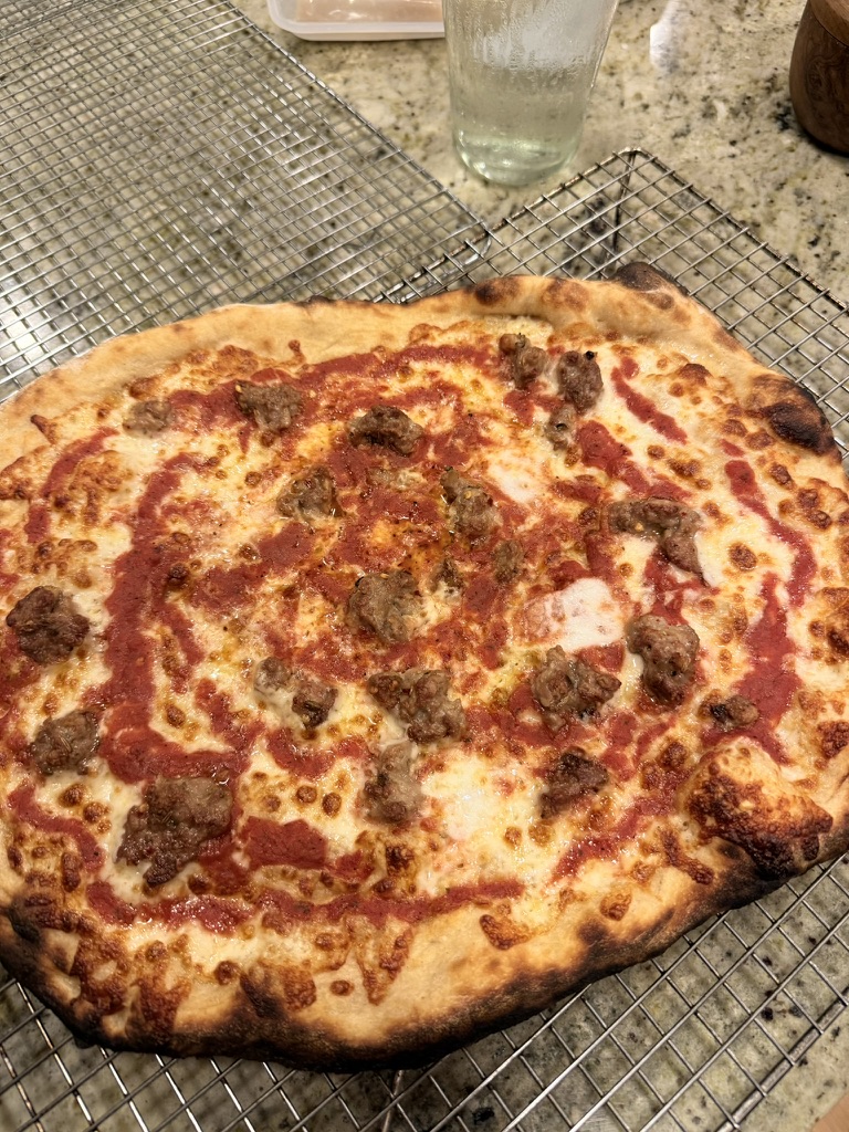 Sausage, Jimmy Nardello pepper, and broccoli raab pizza on a wire cooling rack